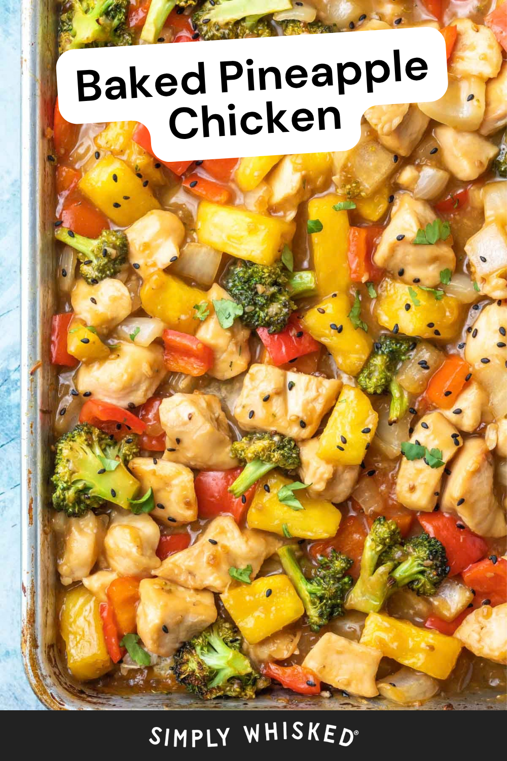 A baking dish filled with pineapple chicken, featuring chunks of juicy chicken, sweet pineapple, broccoli, and red bell peppers, all garnished with black sesame seeds and fresh herbs.