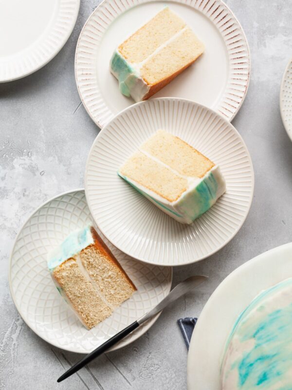White layer cake slices on plates with white and blue marbled frosting