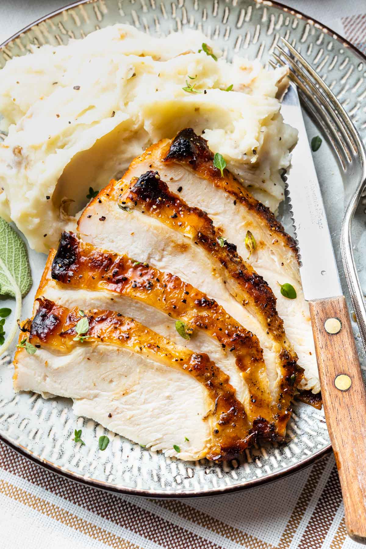 Close up of grilled turkey breast sliced on a plate with mashed potatoes. 