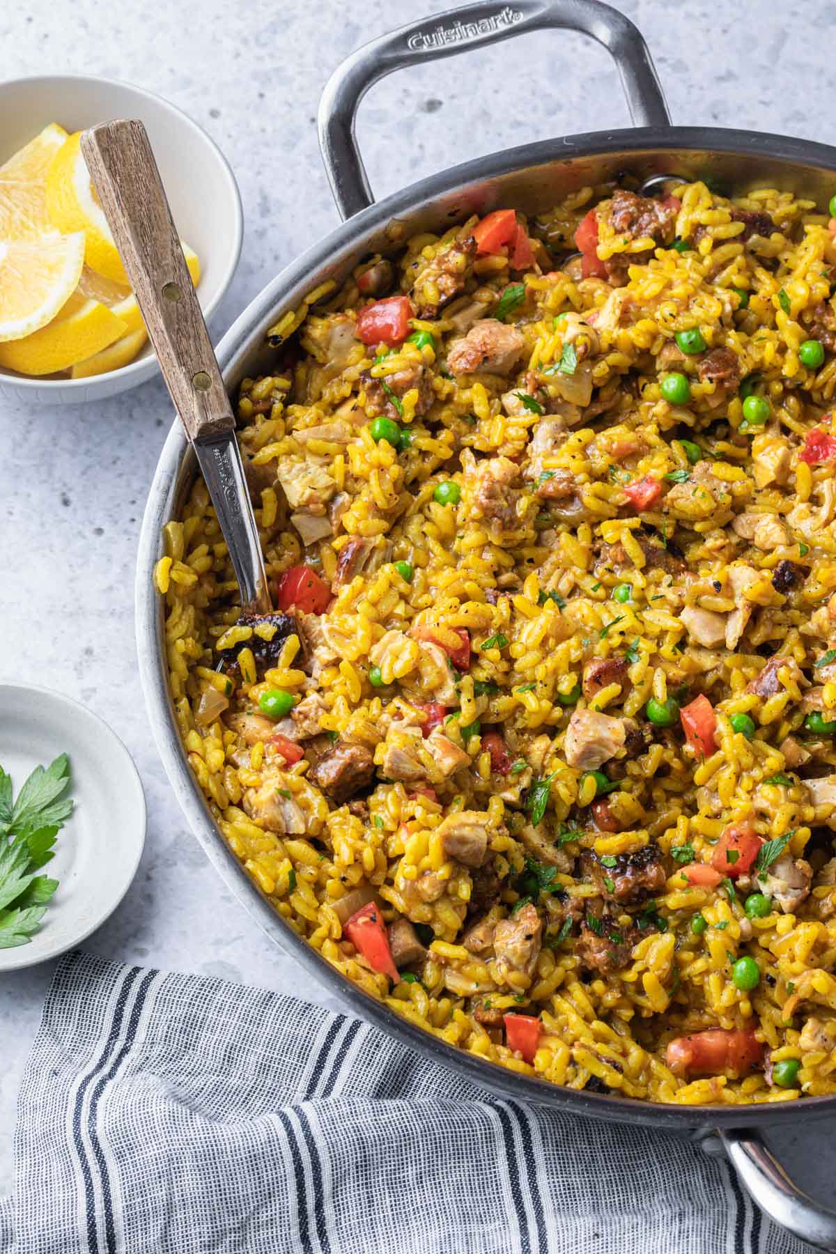 Chicken chorizo paella in a skillet with a serving spoon resting in it.