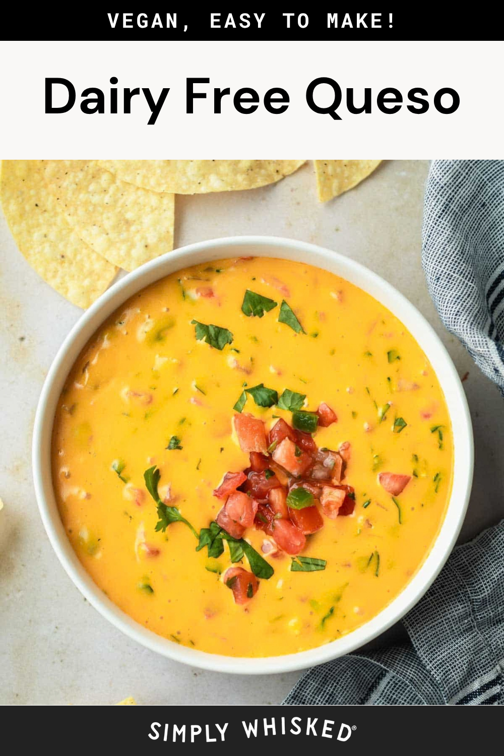 A bowl of creamy Vegan Queso, completely dairy-free and topped with diced tomatoes and herbs, is surrounded by tortilla chips on a light surface.