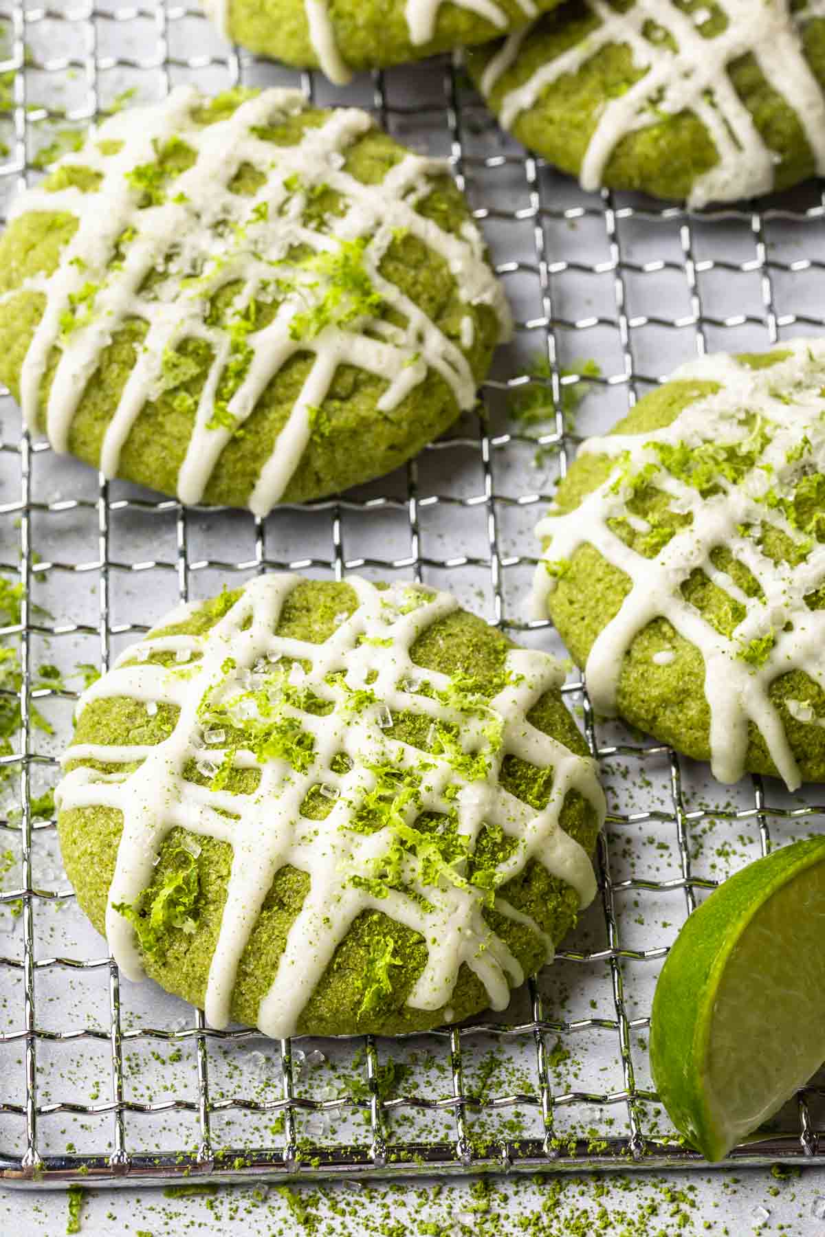 Close up of lime matcha cookies topped with white chocolate drizzle and fresh lime zest. 