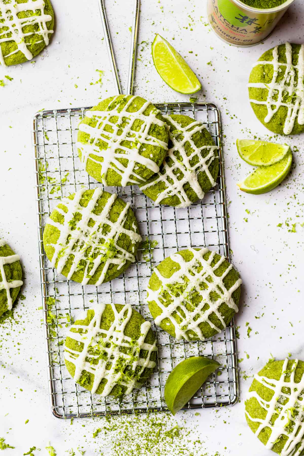 Lime matcha cookies on a cooling rack topped with white chocholate drizzle and fresh lime zest. 