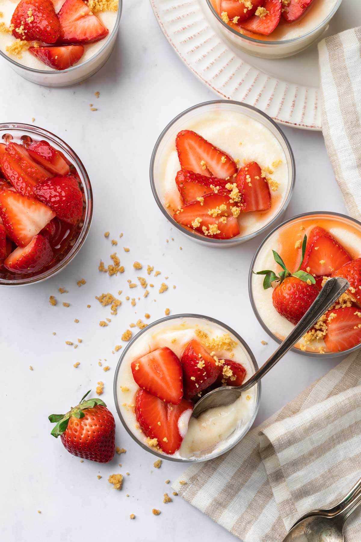 Dairy free cheesecake pudding cups topped with sliced strawberries and graham crumbs. 