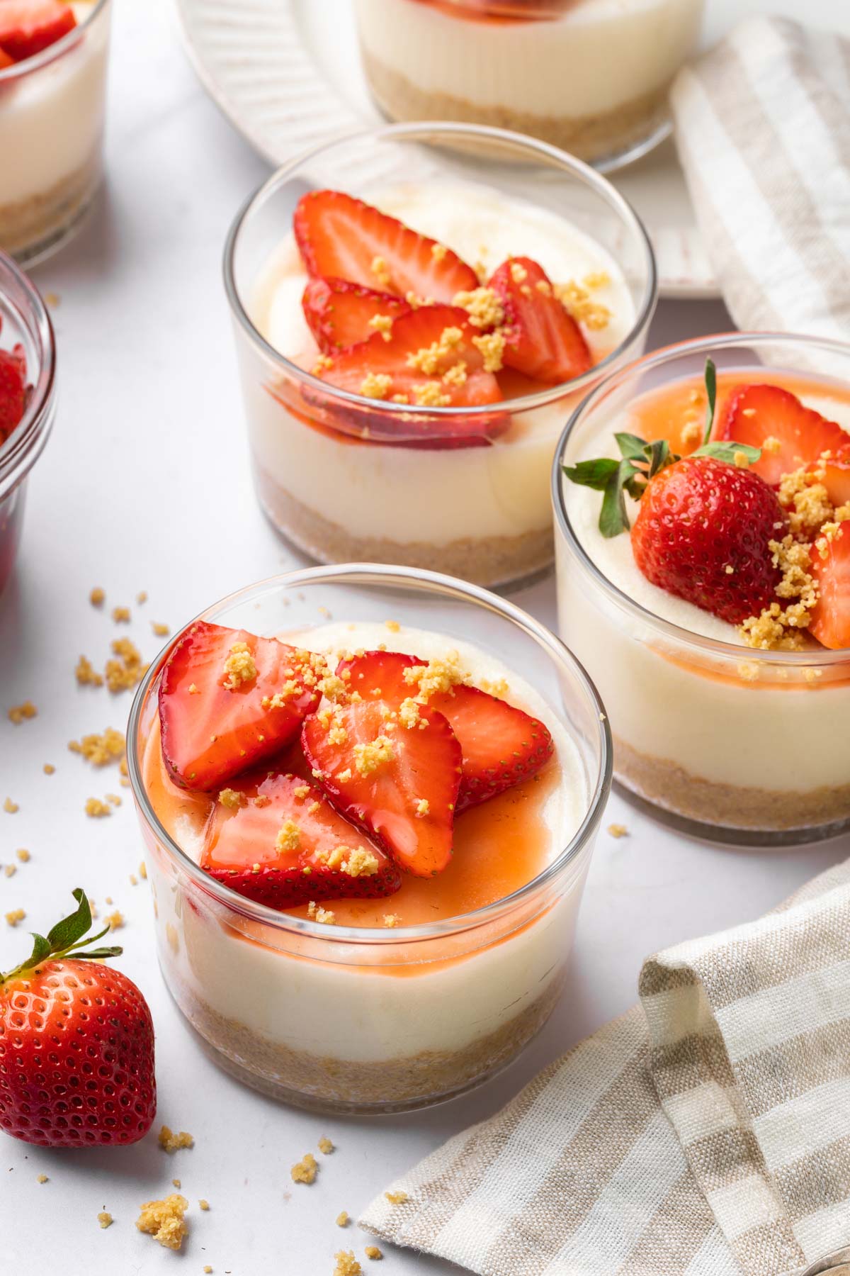Dairy free cheesecake pudding cups topped with sliced strawberries and graham crumbs. 