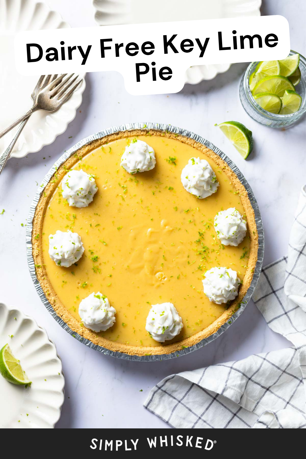 A dairy free key lime pie topped with whipped cream dollops and a sprinkle of lime zest sits invitingly, surrounded by plates, forks, lime wedges, and a napkin. Text above reads Dairy Free Key Lime Pie.