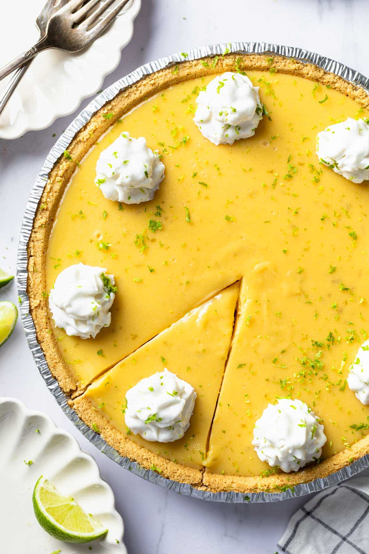 An overhead shot of a dairy free key lime pie topped with whipped cream and lime zest. 