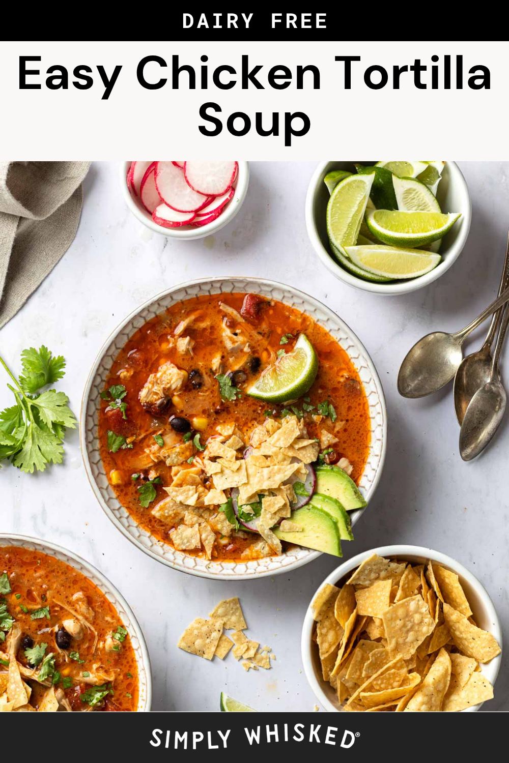 Two bowls of chicken tortilla soup topped with avocado and crushed chips, surrounded by lime wedges, sliced radishes, fresh cilantro, and a bowl of tortilla chips on a white surface. This vibrant display highlights the classic flavors and colorful garnishes that make chicken tortilla soup so inviting.