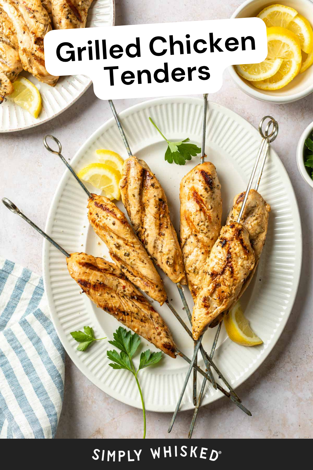 Four grilled chicken tenders on metal skewers sit on a white plate with lemon wedges and parsley, next to a striped napkin. Text reads Grilled Chicken Tenders and Simply Whisked, highlighting these juicy grilled chicken tenders as the perfect centerpiece for your next meal.