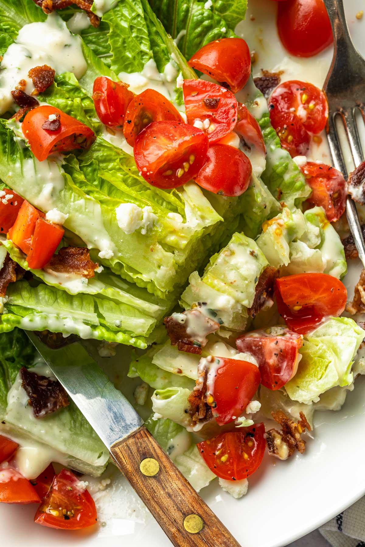 Close up of a wedge salad with tomatoes bacon and dairy free blue cheese dressing. 