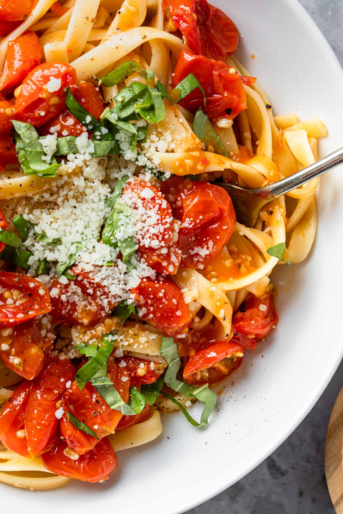 Close up of roasted tomato pasta topped with fresh basil and dairy free parmesan cheese. 