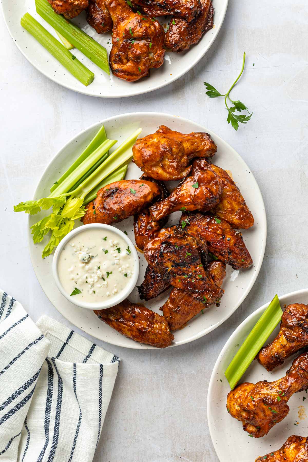 Buffalo wings on plates with celery and vegan blue cheese dressing. 