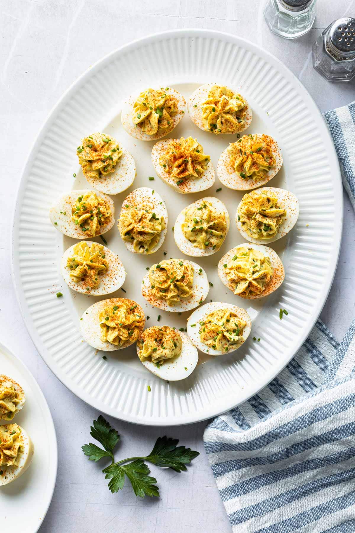 A platter of smoked deviled eggs garnished with smoked paprika and fresh chopped chives. 