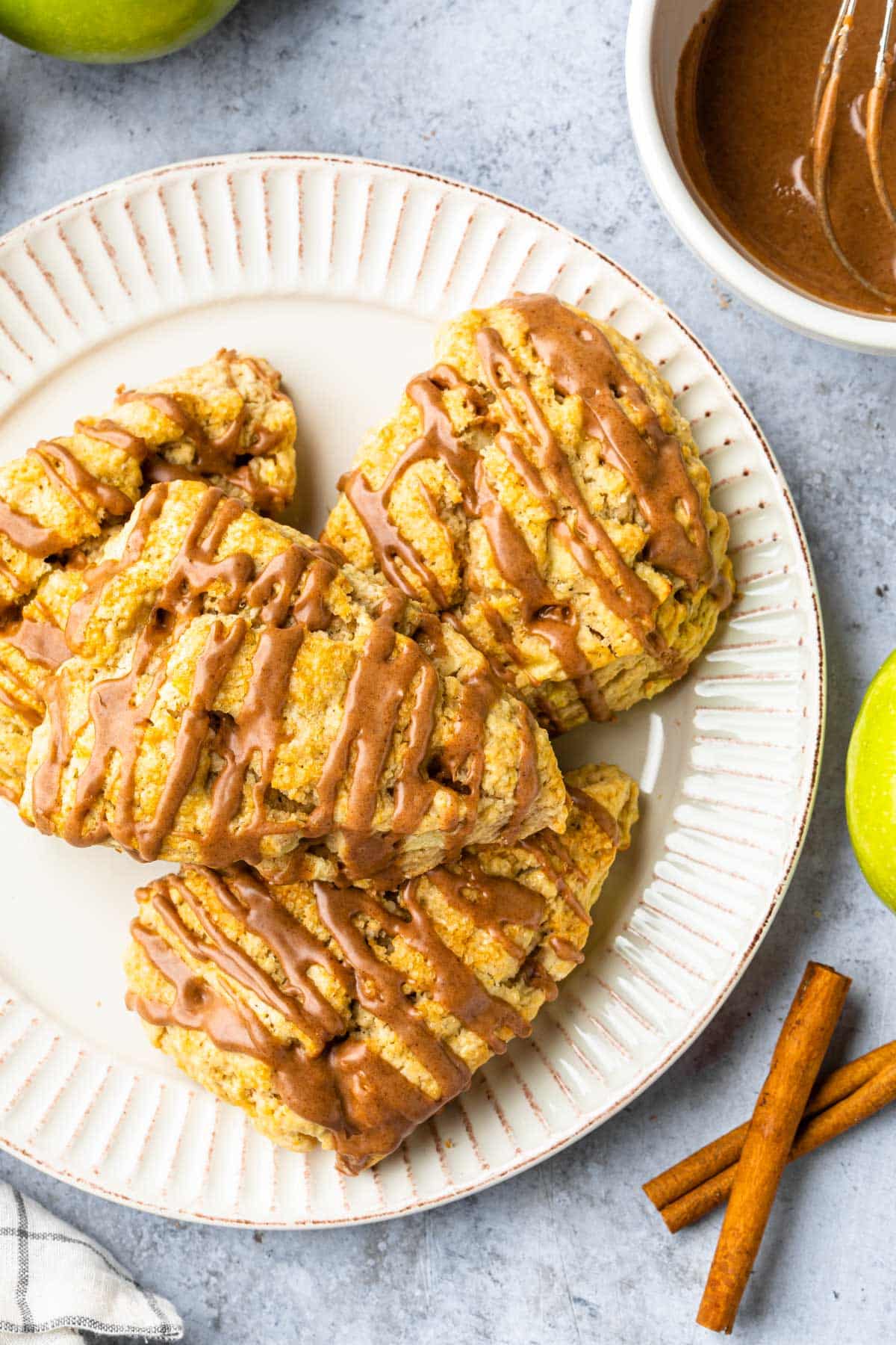 Apple scones on a plate, drizzled with cinnamon frosting. 