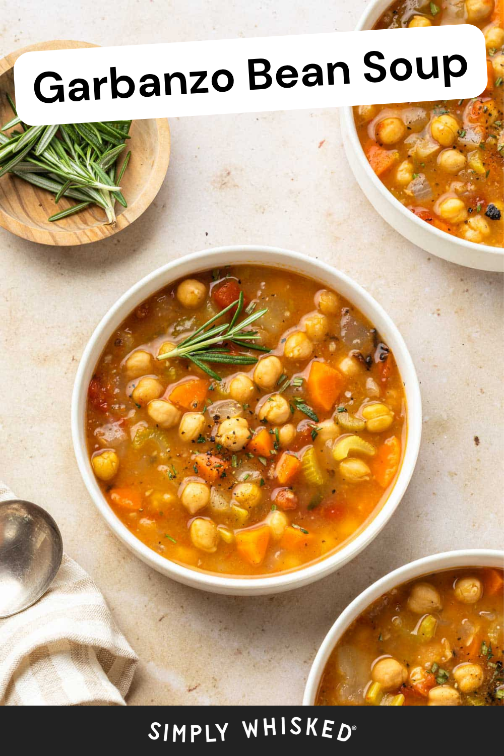 Overhead view of bowls of Garbanzo Bean Soup with vegetables, garnished with fresh rosemary. A small wooden bowl of rosemary and a spoon are nearby. Text reads Garbanzo Bean Soup and Simply Whisked.