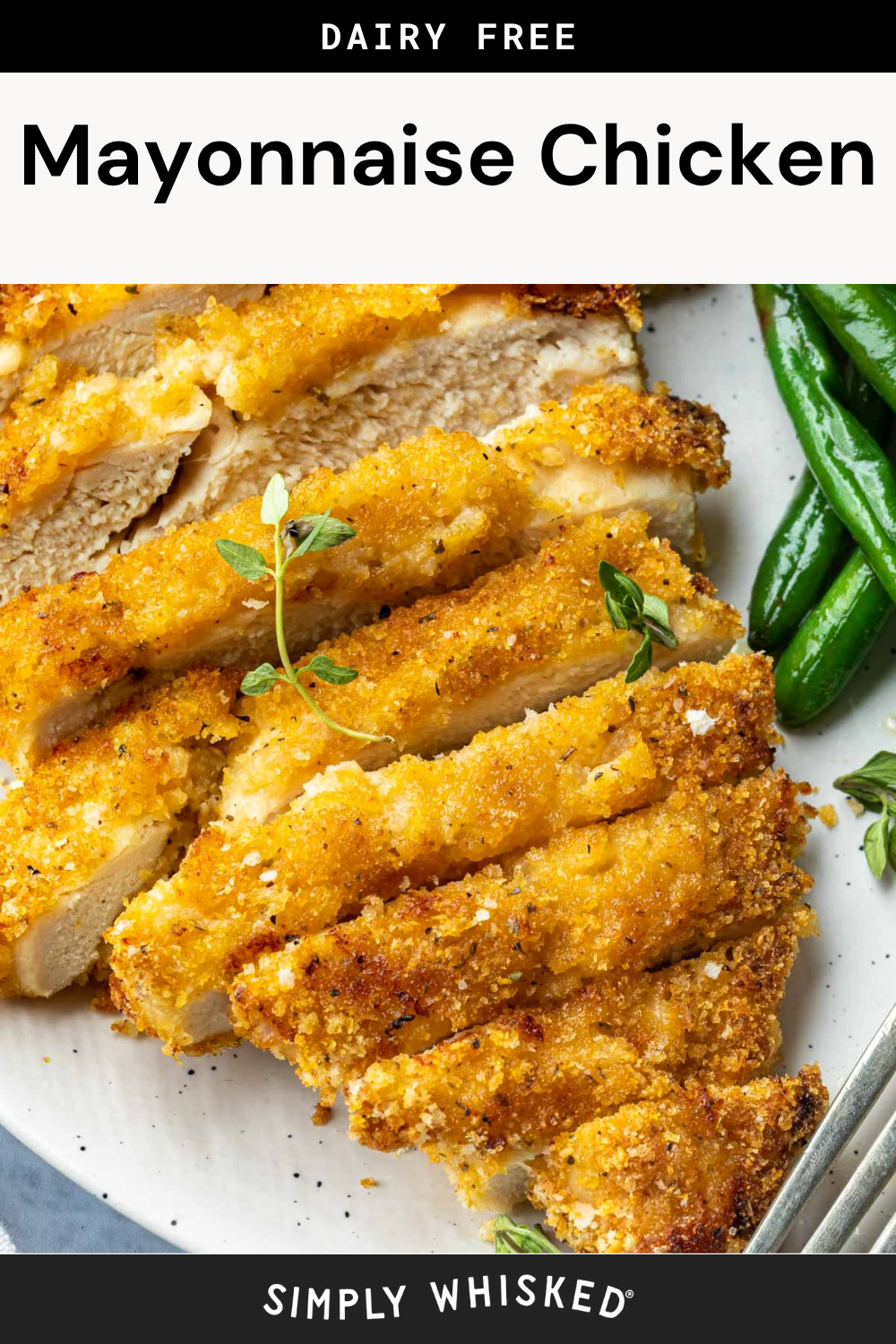 Close-up of sliced, golden-brown Mayonnaise Chicken garnished with fresh herbs on a white plate, served with green beans. Text above reads “Dairy Free Mayonnaise Chicken,” and below reads “Simply Whisked.”.