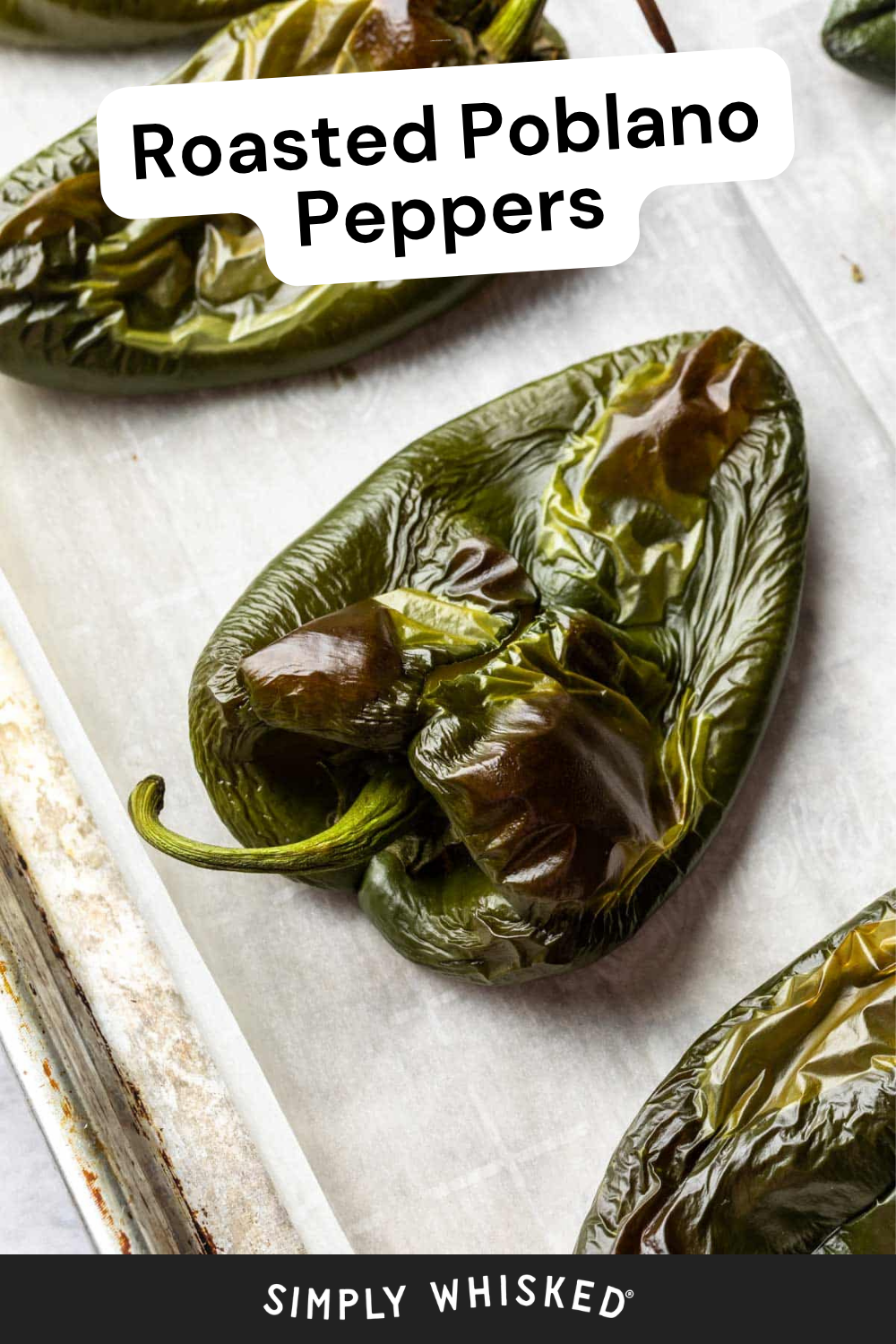 Close-up of roasted poblano peppers on a parchment-lined baking sheet. The text Roasted Poblano Peppers appears at the top, and Simply Whisked is written at the bottom, highlighting these perfectly roasted poblano peppers.