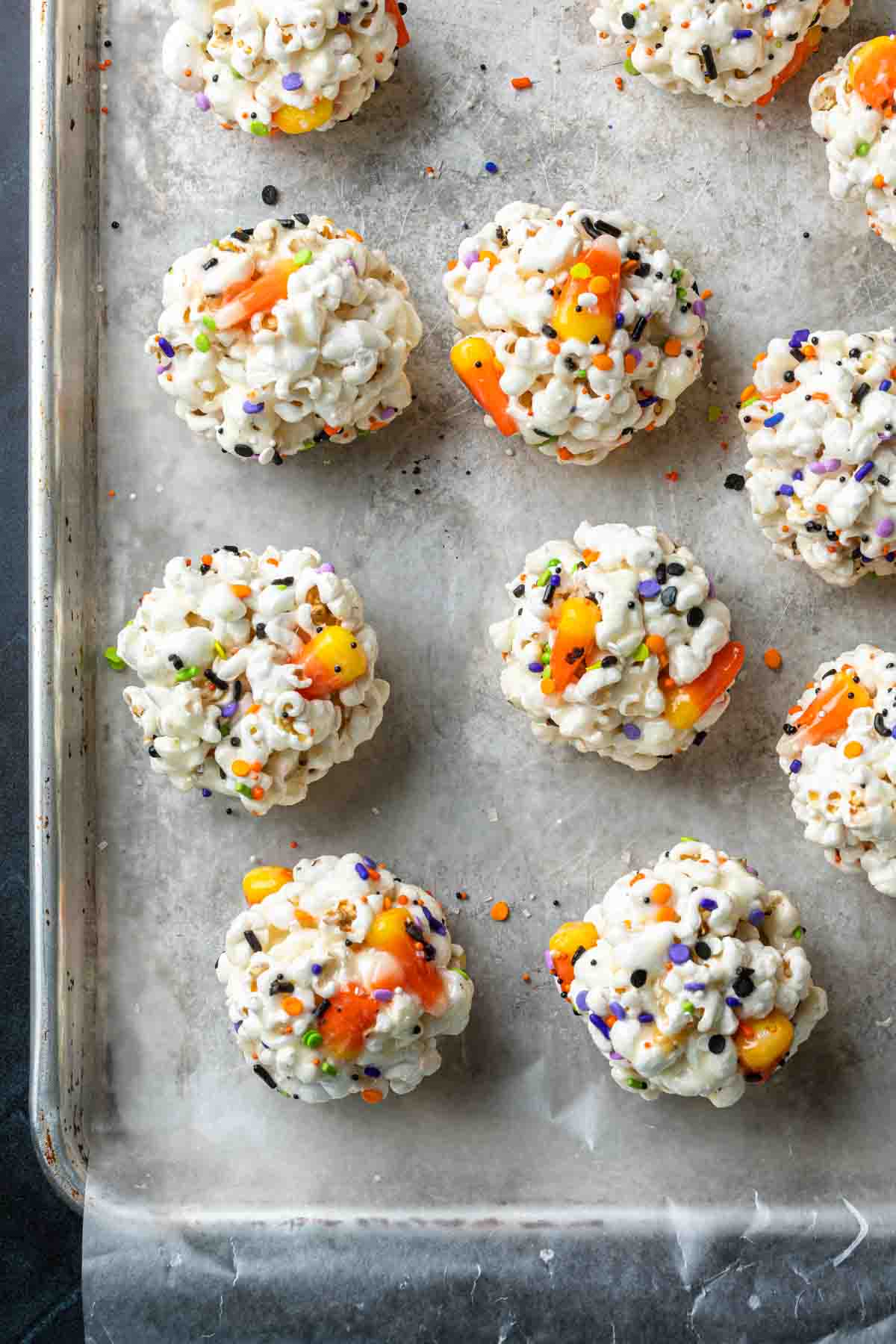 Halloween popcorn balls on a baking sheet lined with parchment paper. 