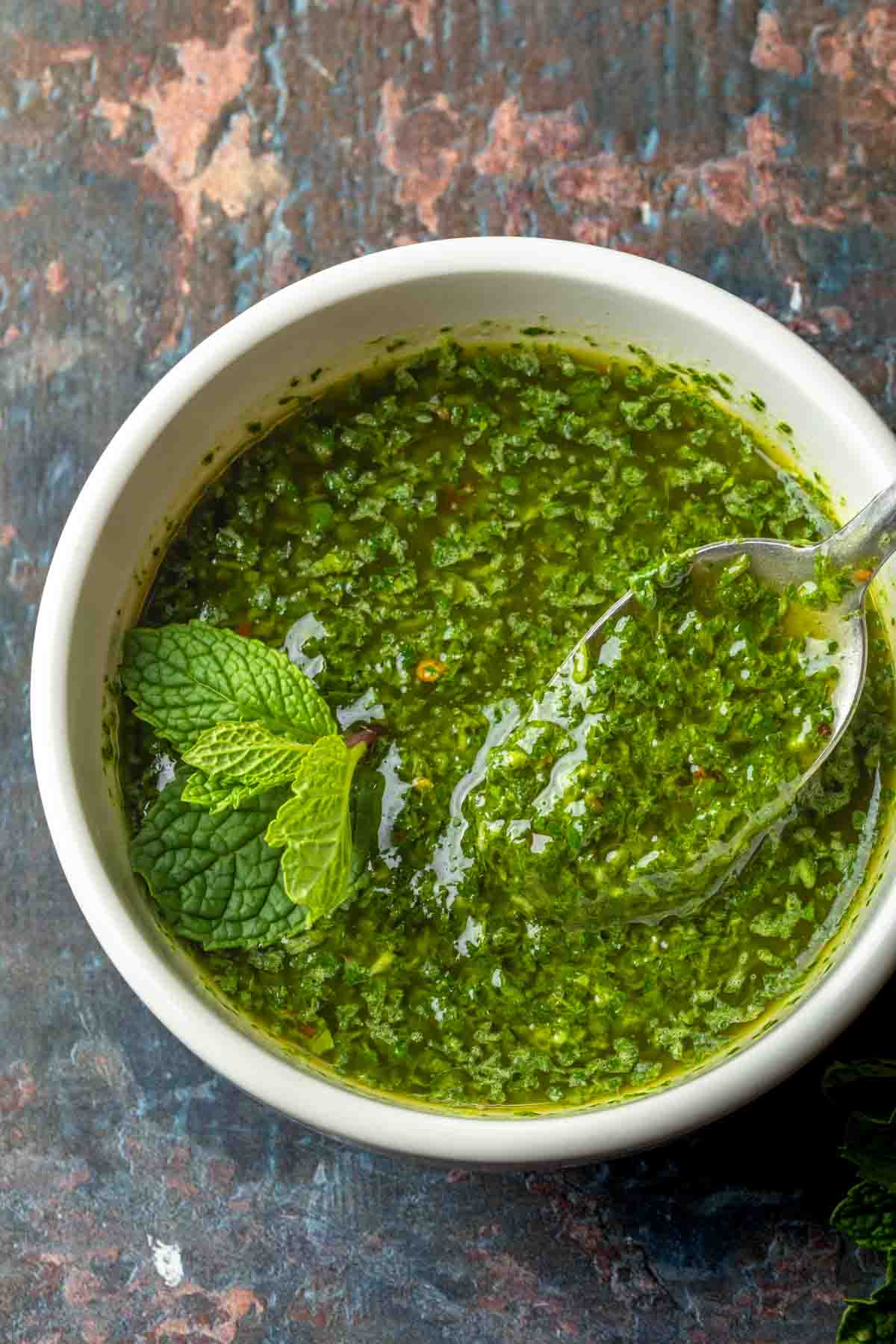 Chimichurri sauce with mint in a bowl with a spoon. 