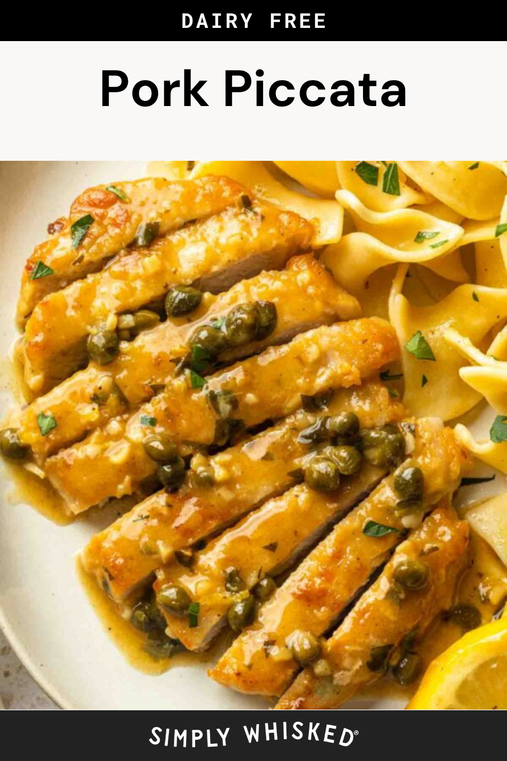 Pork piccata is served sliced and topped with capers and a tangy sauce, nestled beside tender egg noodles and a fresh lemon wedge on a white plate.