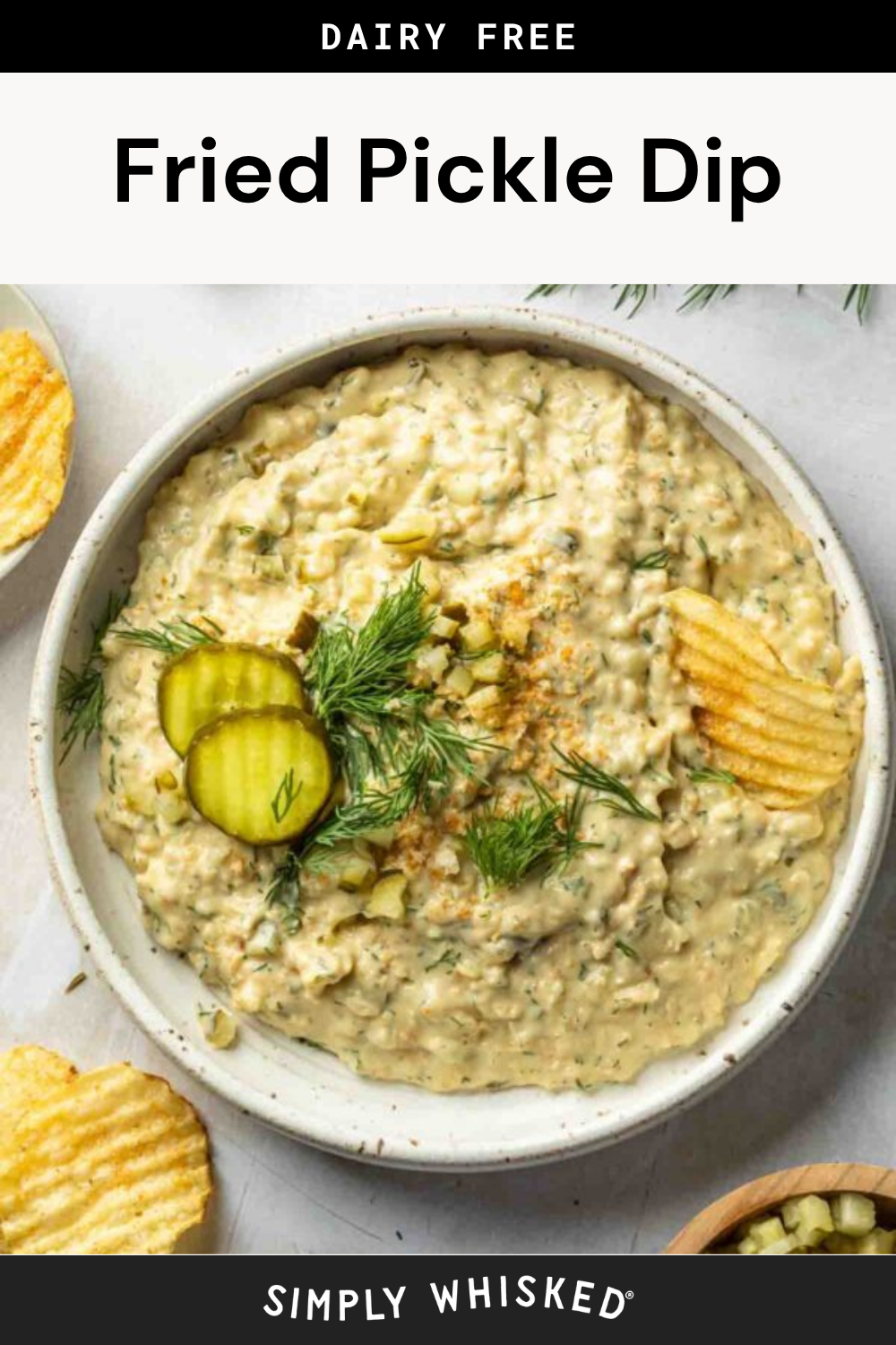 A bowl of creamy fried pickle dip topped with pickle slices, fresh dill, and potato chips, surrounded by more chips and a sprinkle of herbs. The image features text: Dairy Free Fried Pickle Dip and Simply Whisked.