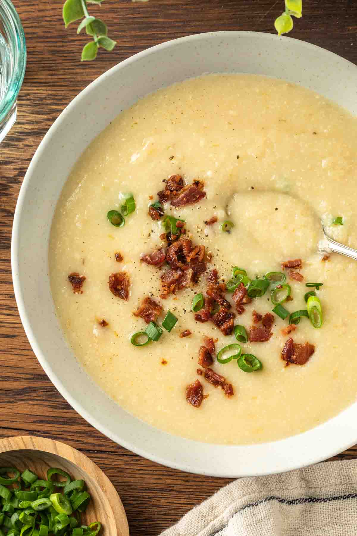 A bowl of cauliflower potato soup garnished with bacon and green onions. 
