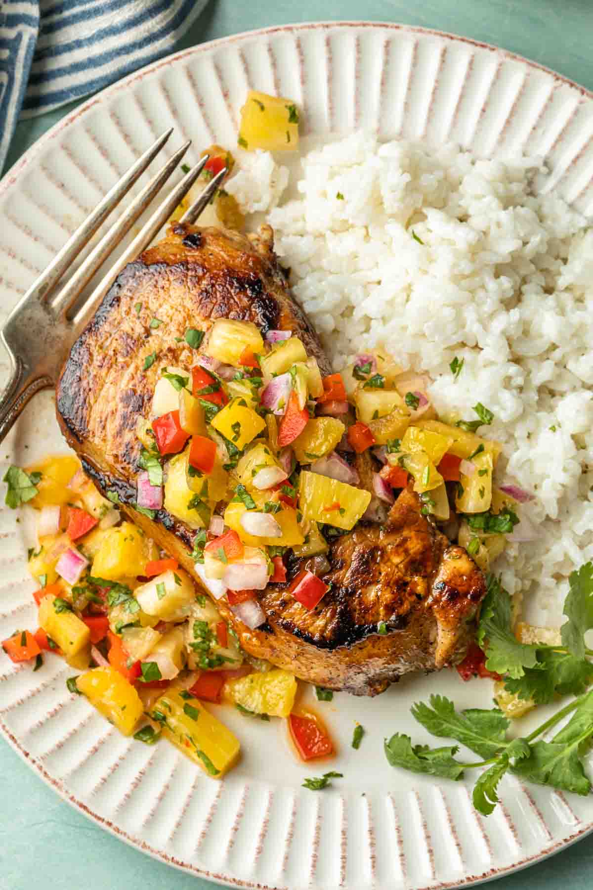 A thick cut, seared pork chop topped with pineapple salsa served over a bed of coconut rice. 