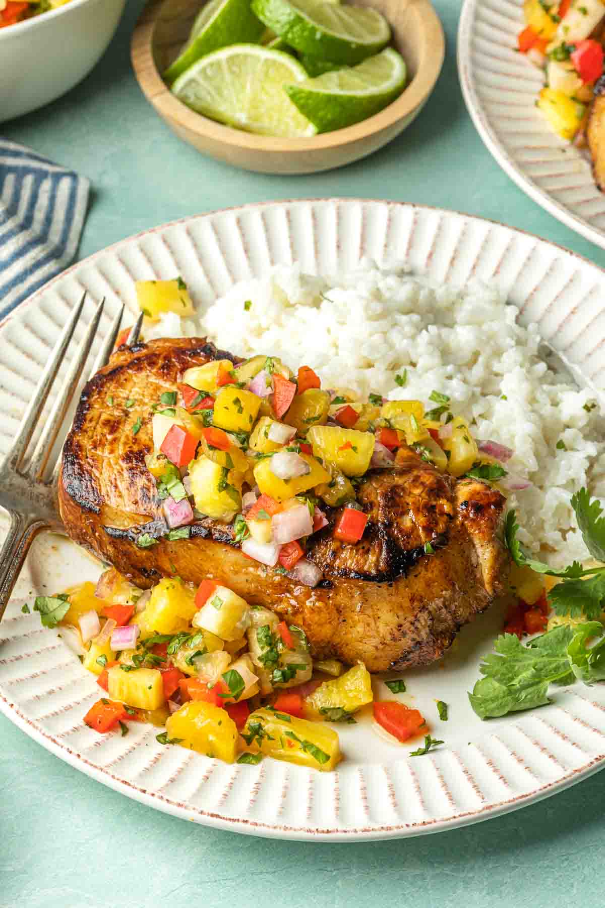 A pineapple pork chop on a plate with coconut rice. 