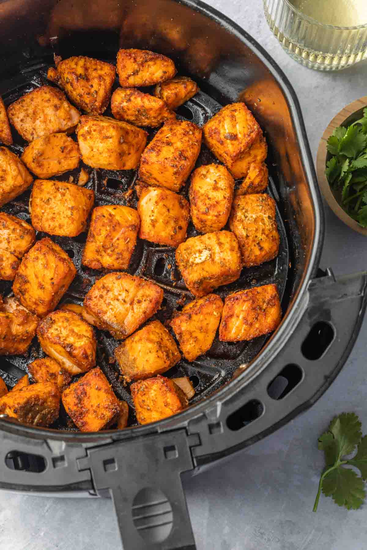 Pieces of salmon in an air fryer basket. 