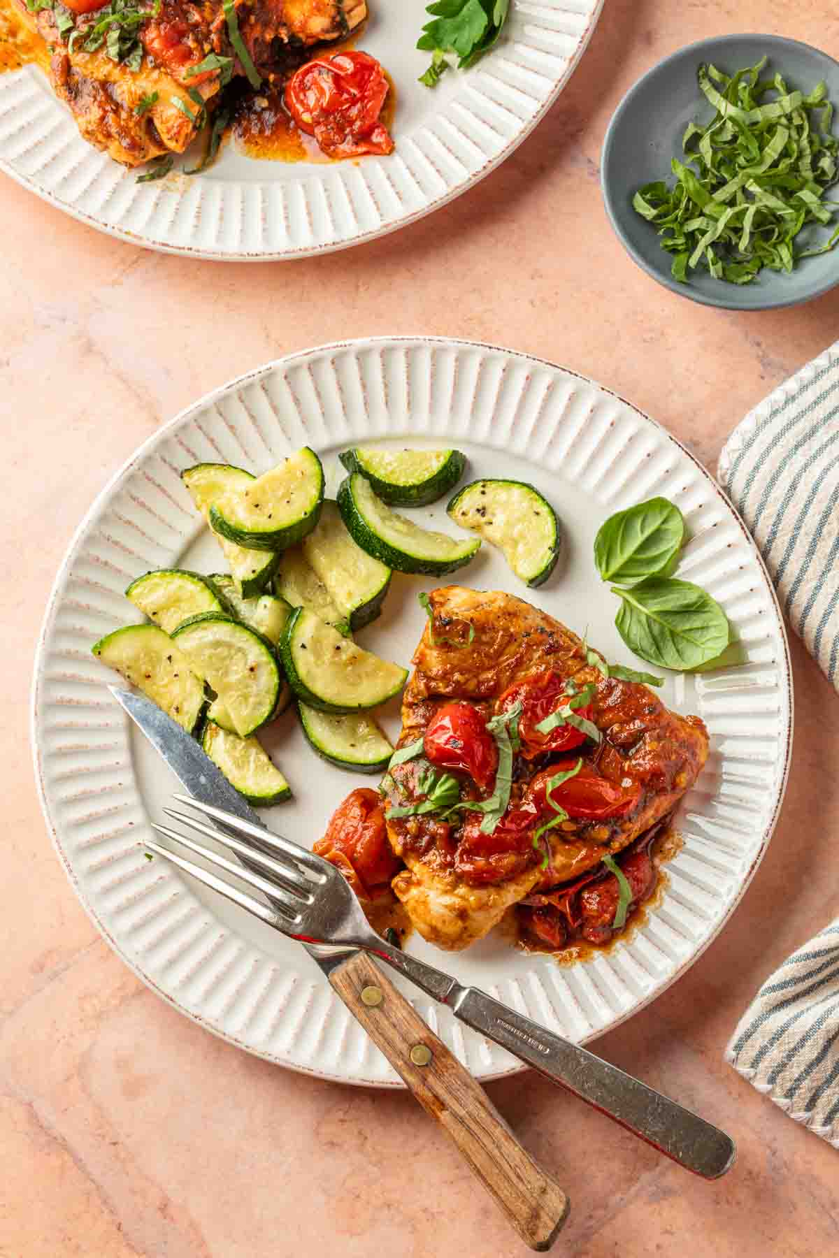 Chicken pomodoro on a plate with roasted zucchini slices.