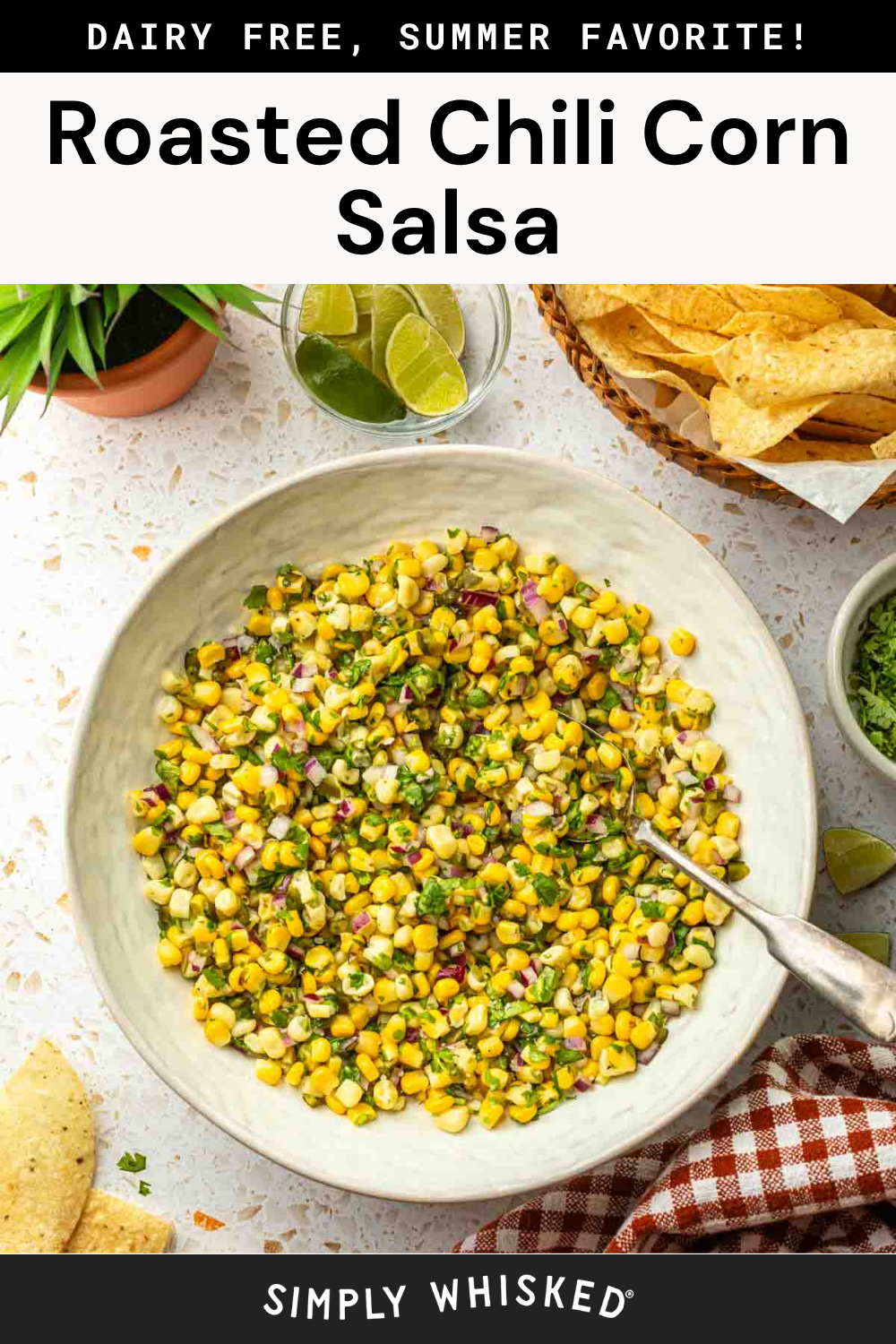 A large bowl of Roasted Chili Corn Salsa with diced vegetables sits on a table beside tortilla chips, lime wedges, a green plant, and a red-checked napkin. Text above reads: “Roasted Chili Corn Salsa.”.