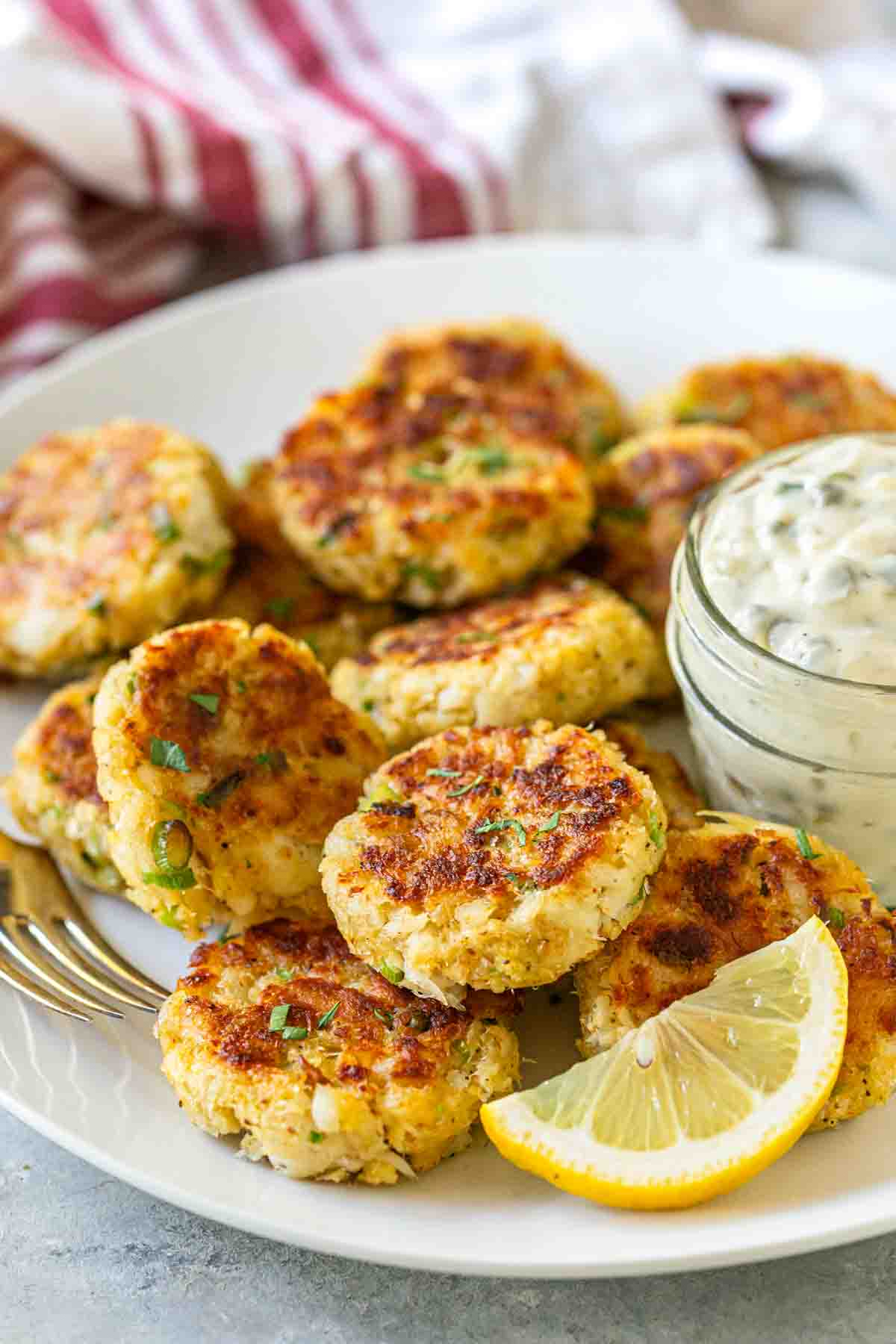 A serving platter with a dozen fish cakes and a lemon wedge. 