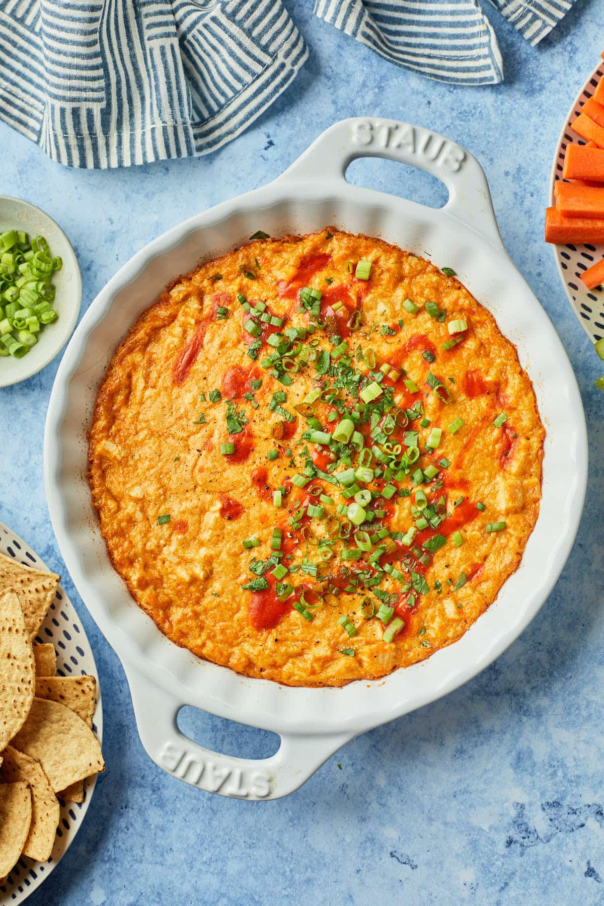 An overhead photo of dairy free buffalo chicken dip garnished with green onion and a drizzle of hot sauce. 