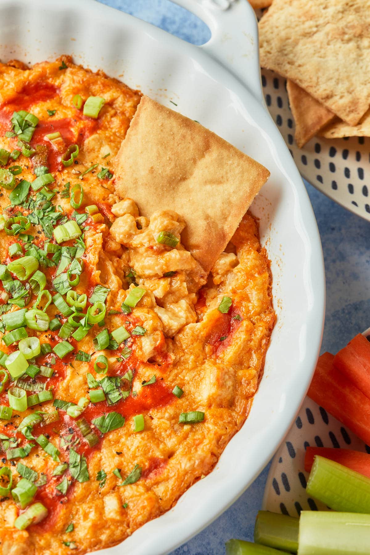 Close up of a pit chip dipped into a dairy free hot sauce dip baked in a pie plate. 