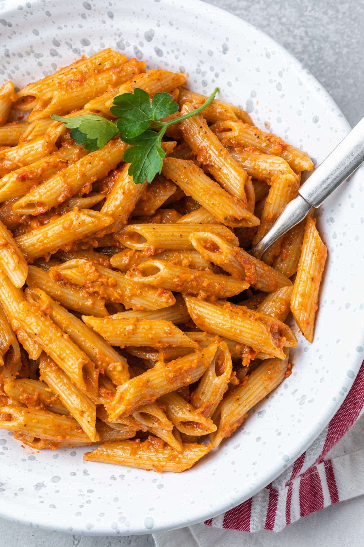 A bowl of pasta in a red pesto sauce. 