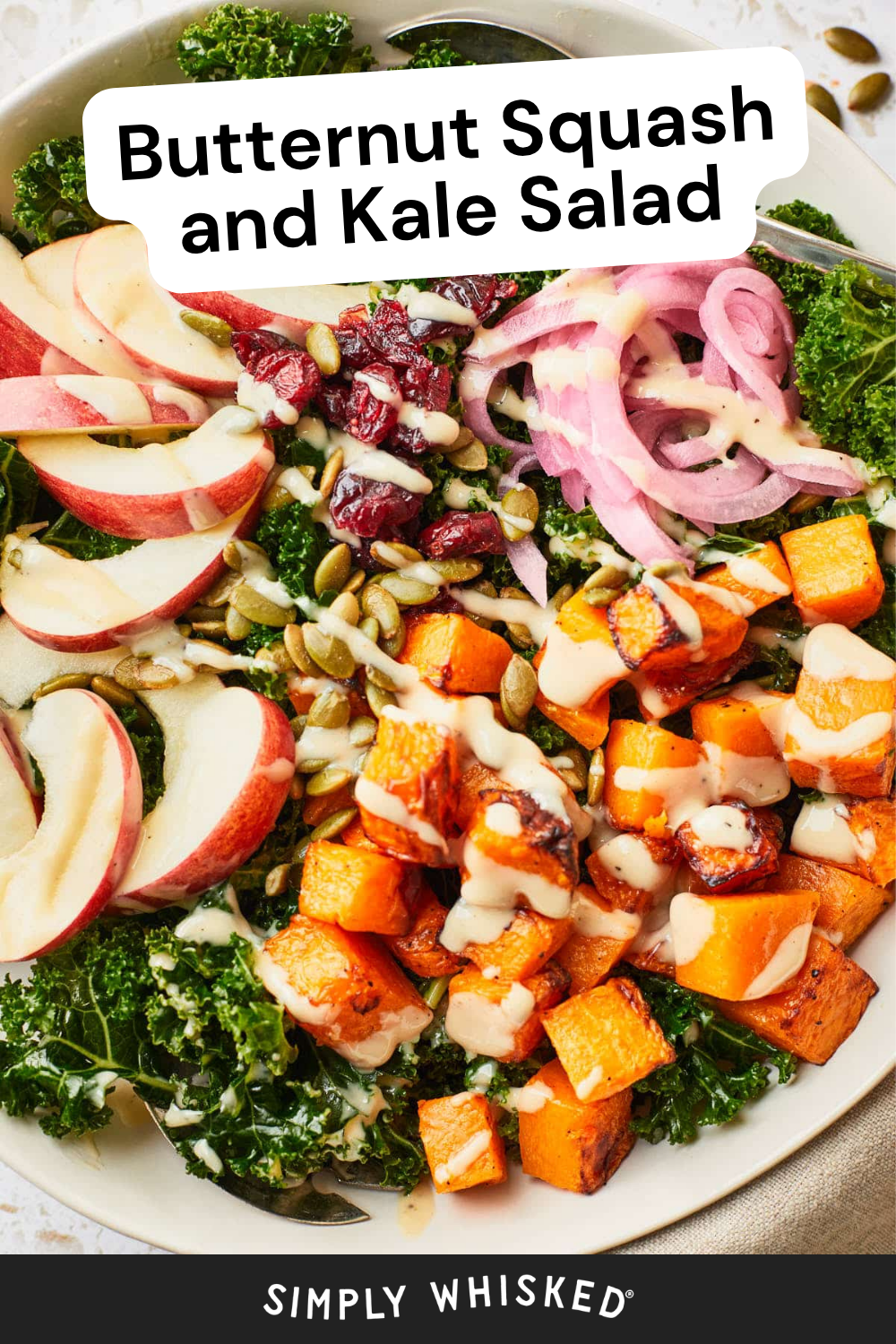 A bowl of Butternut Squash and Kale Salad featuring fresh kale, juicy apple slices, roasted butternut squash cubes, tangy pickled onions, sweet cranberries, crunchy pepitas, and a creamy dressing—an irresistible blend labeled Butternut Squash and Kale Salad.