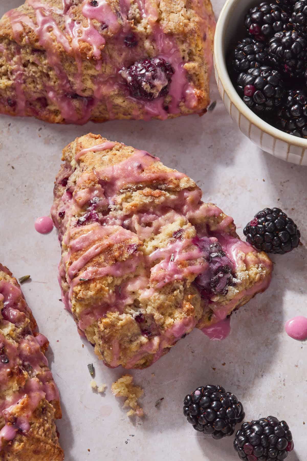 Close up of a few lavender blackberry scones glazed with a purple glaze.
