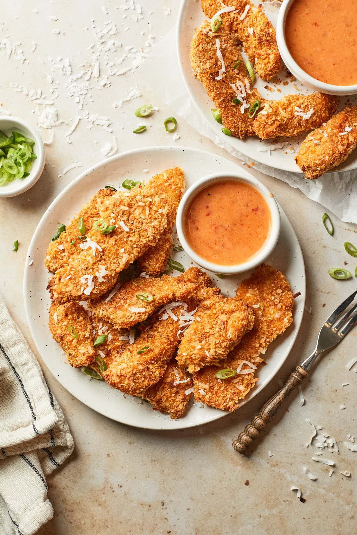 A couple plates of coconut chicken tenders with dipping sauce.