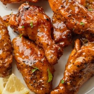 Close up of chicken pieces on a plate, tossed in a sweet and tangy sauce.