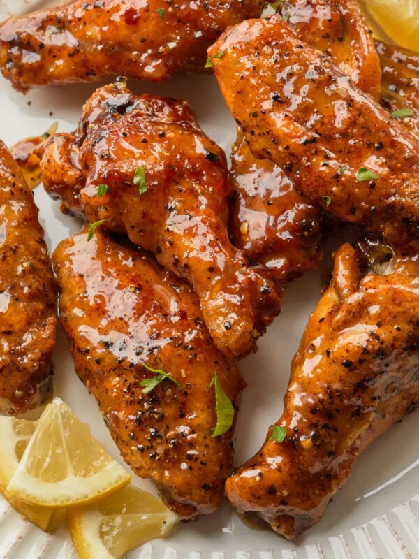 Close up of chicken pieces on a plate, tossed in a sweet and tangy sauce.