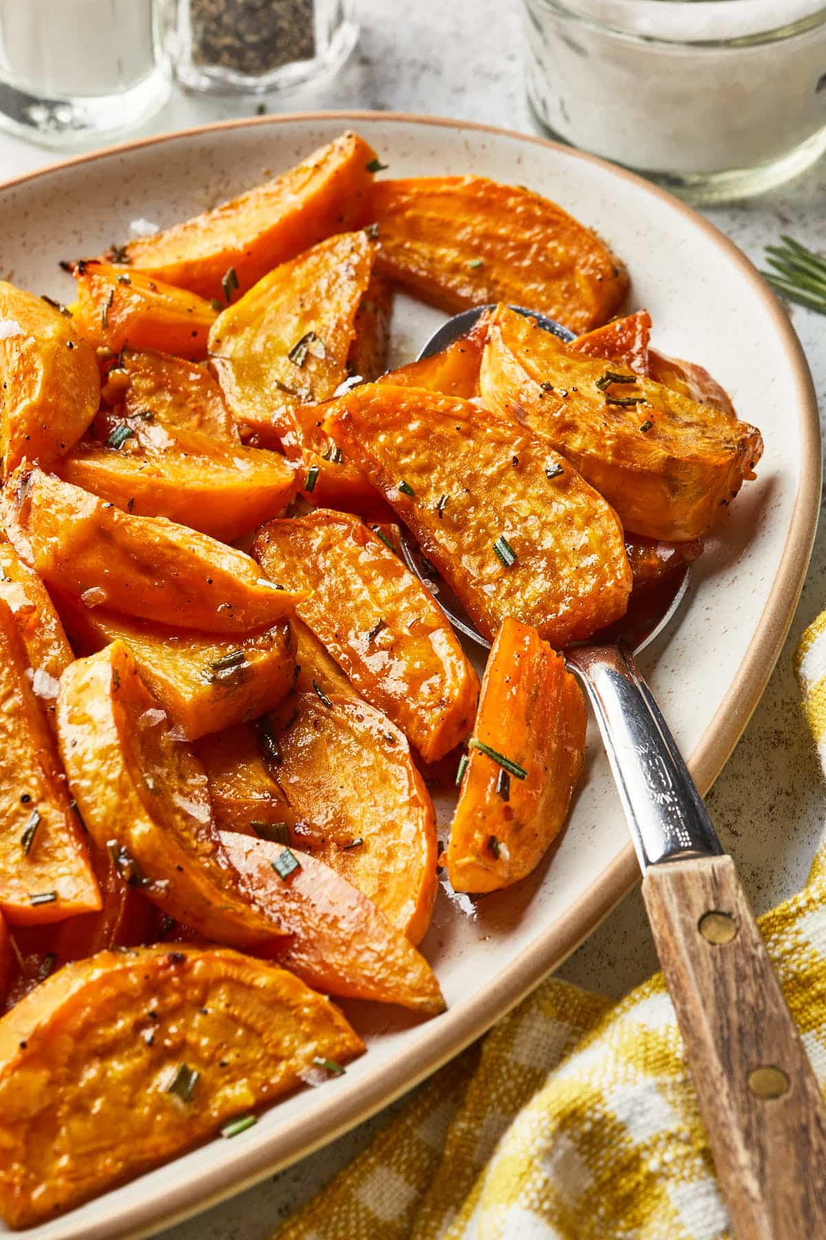 Golden beets roasted with rosemary and honey, on a serving platter with a serving spoon. 