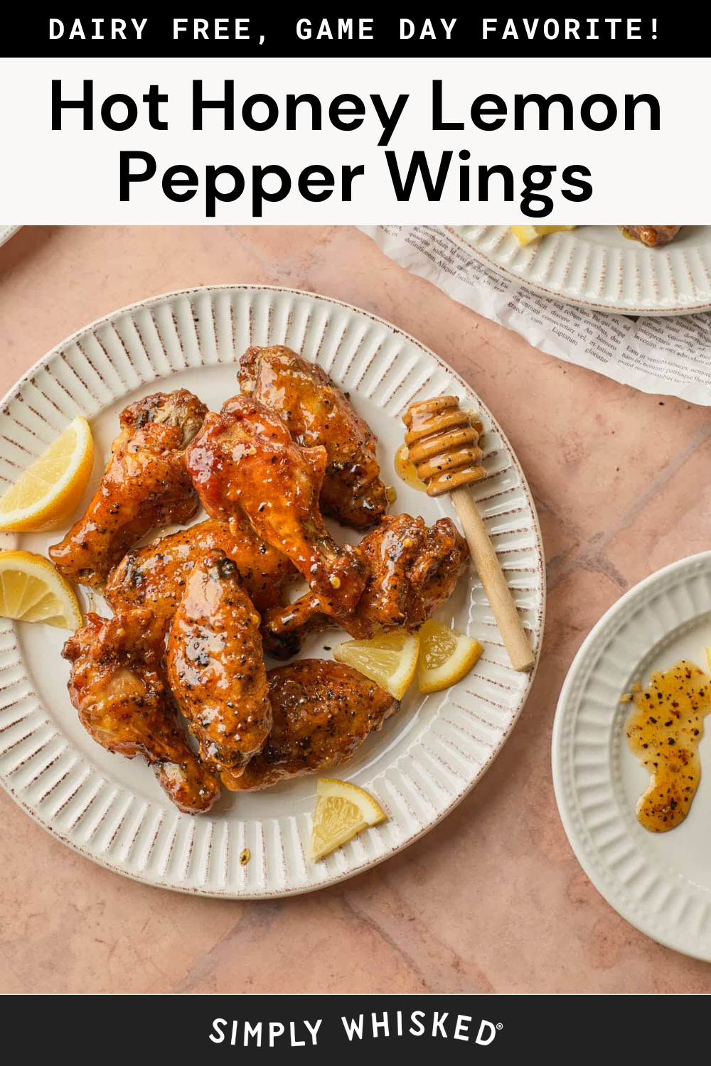 A plate of Honey Lemon Pepper Wings, glazed to perfection and garnished with lemon wedges and a honey dipper, sits on a pink surface beside a smaller plate of sauce. Text above reads “Hot Honey Lemon Pepper Wings.”.