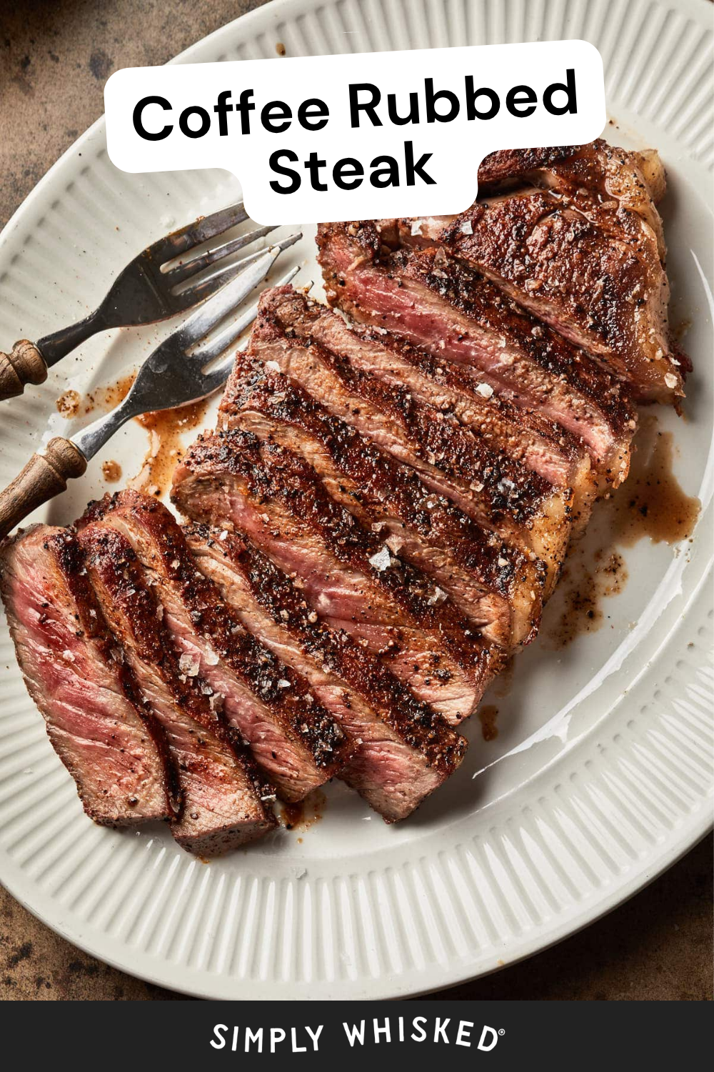 A sliced, medium-rare coffee rubbed steak is served on a white oval plate with two forks. Text reads “Coffee Rubbed Steak” at the top and “Simply Whisked” at the bottom.