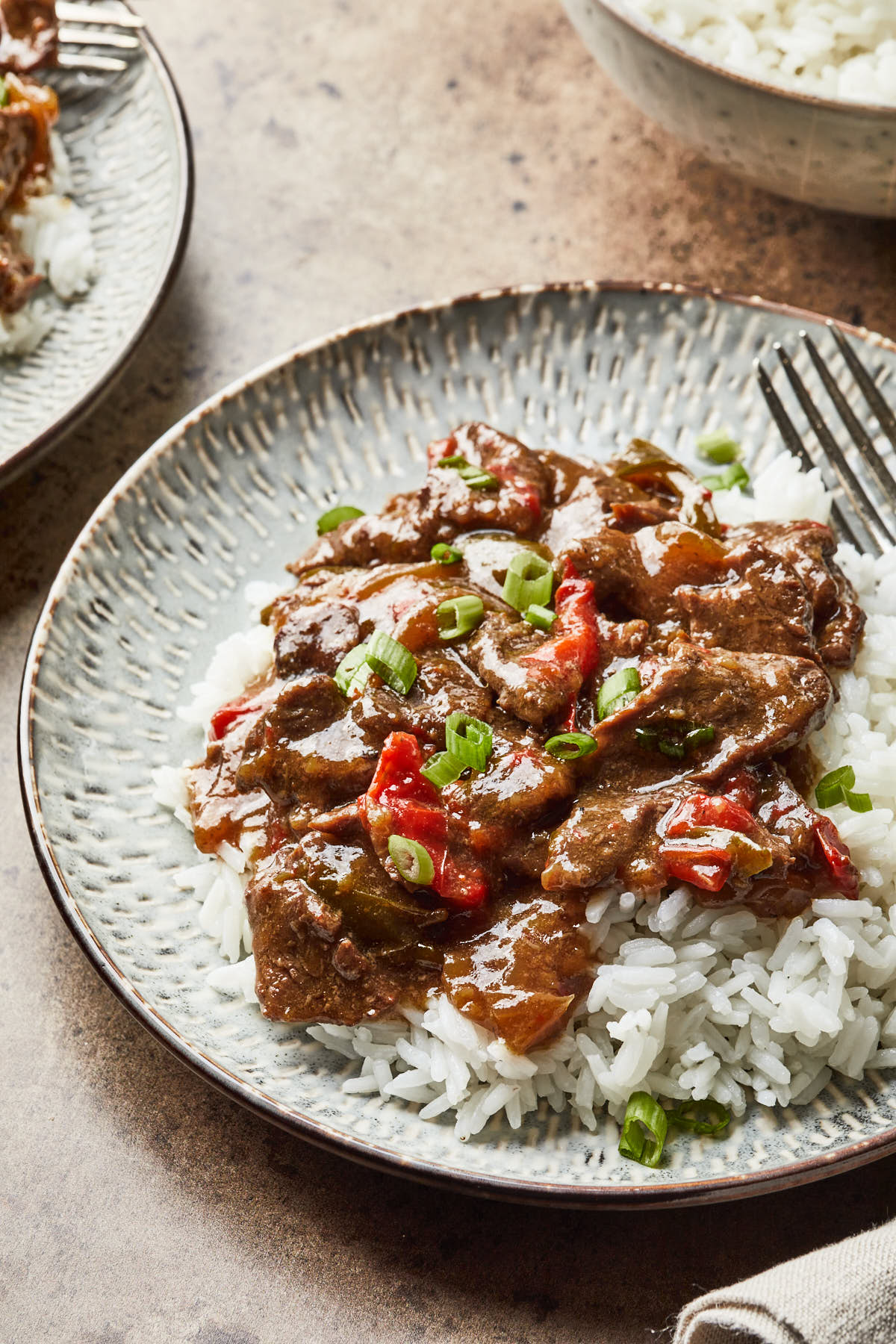 A plate of pepper steak over white rice.