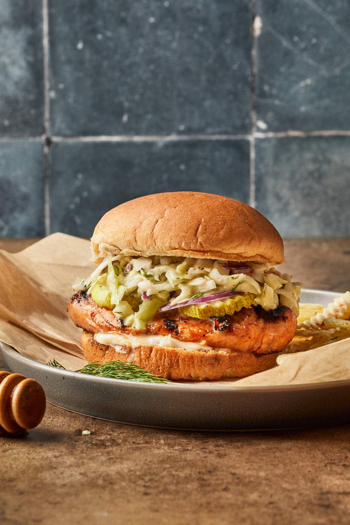 A side view of a chicken sandwich piled high with pickle slaw.