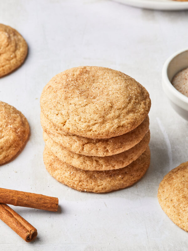 A stack of dairy free snickerdoodle cookies, next to a few cinnamon sticks.