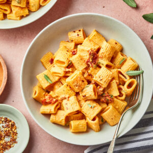 creamy pumpkin rigatoni with sun dried tomatoes garnished with sage