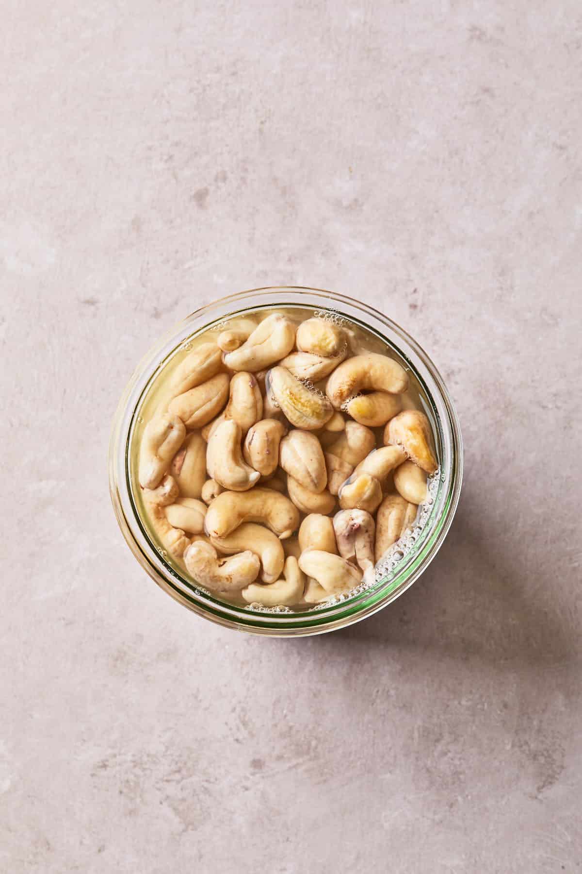 raw cashews in a mason jar soaking with water