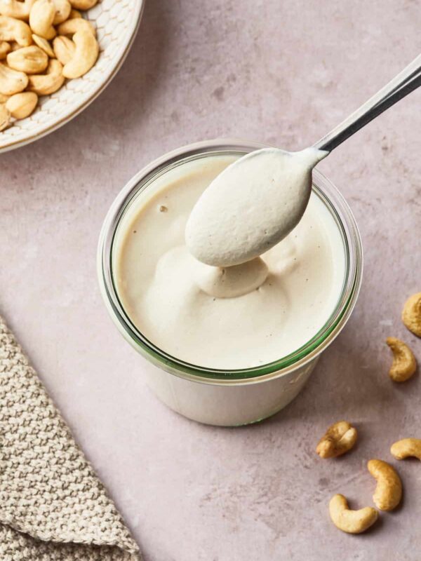a spoon stirring a mason jar of cashew cream