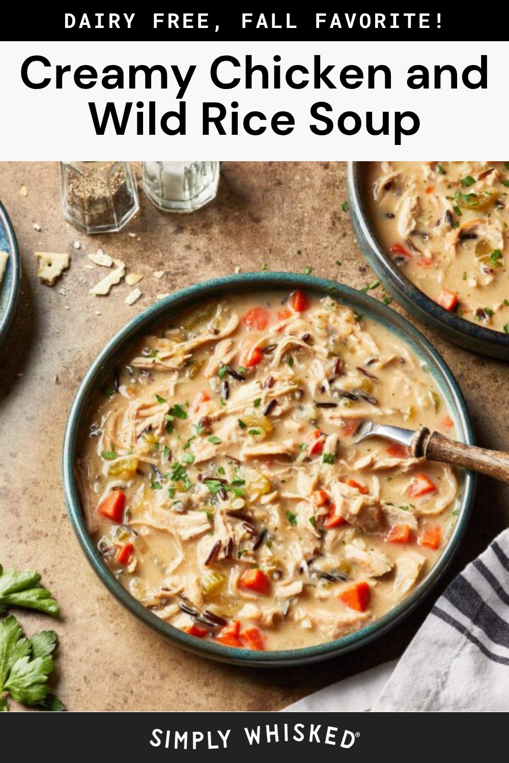 Two bowls of creamy chicken and wild rice soup, garnished with parsley, sit on a table alongside a wooden spoon, salt and pepper shakers, and freshly chopped herbs. Text reads Creamy Chicken and Wild Rice Soup.